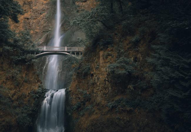 A bridge in front of a waterfall.